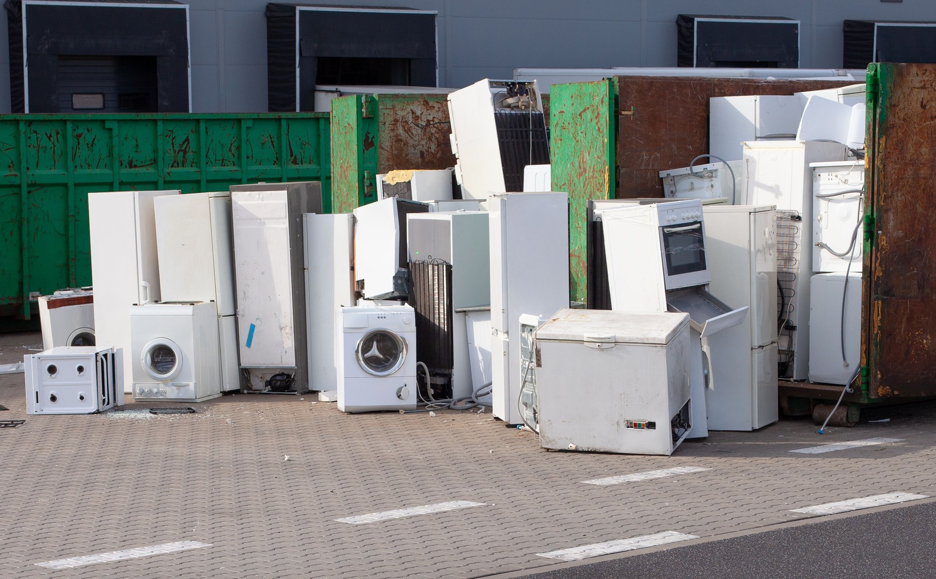 Old electrical appliances, washing machines in container. Consumerism problem .